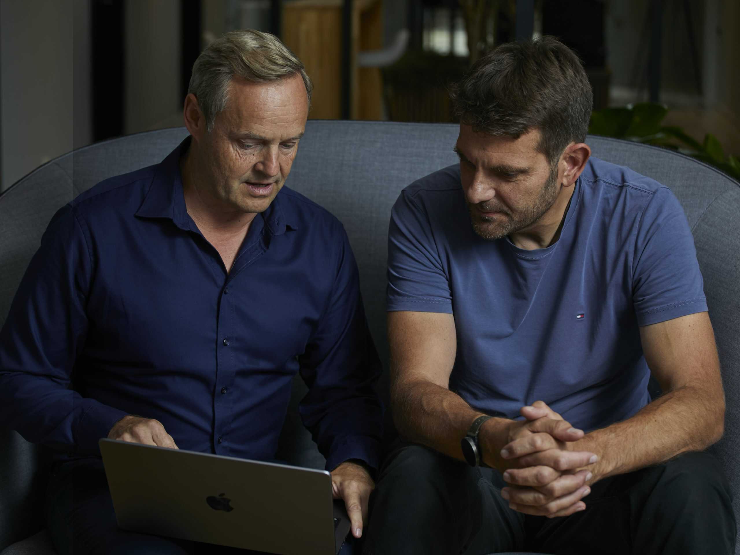 Fredrik og Carsten sidder i en sofa og kigger ned i computeren